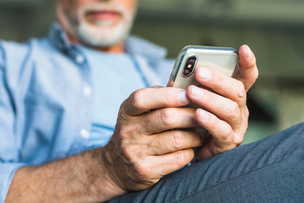 Älterer Mann mit einem Smartphone in der Hand.