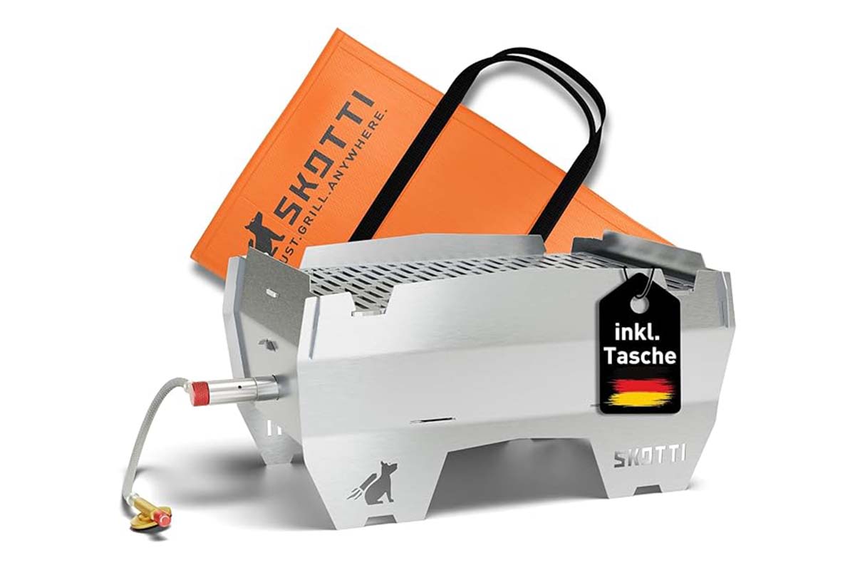 silberner Gasgrill auf weißem Grund, im Hintergrund eine orangefarbene Tasche