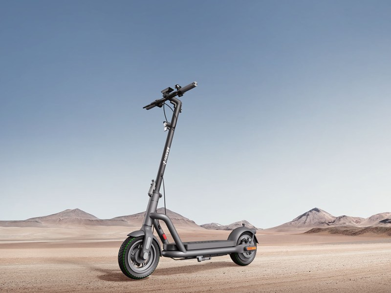 E-Scooter Navee N65i steht im Profil vor einer hügeligen Wüstenlandschaft.