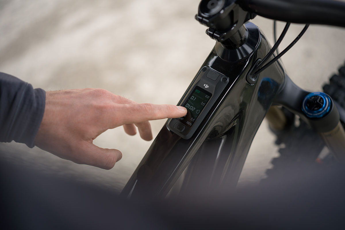 Detailaufnahme die zeigt, wie eine Hand ein Steuerungsmodul bedient, das bei einem E-Mountainbike auf dem Rahmen sitzt.