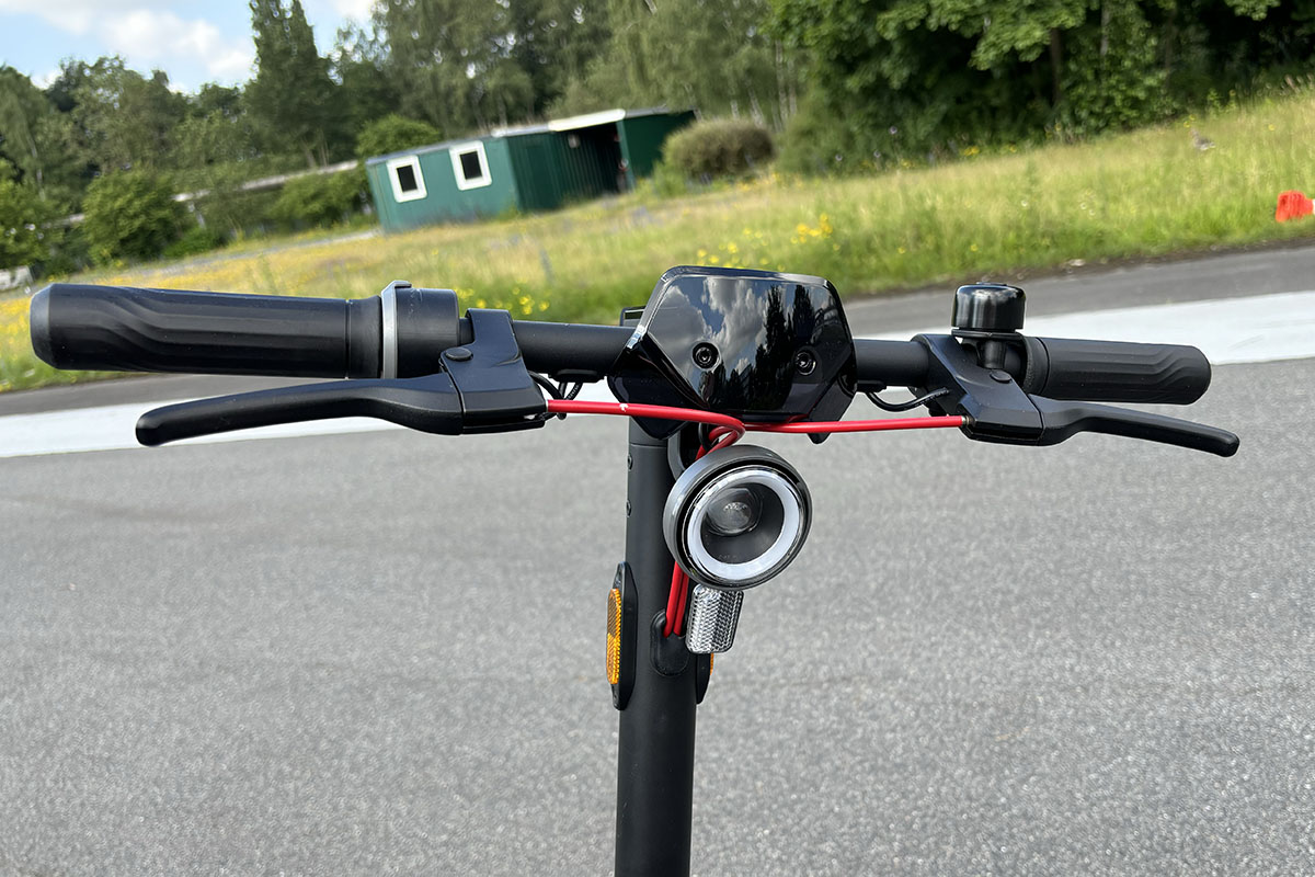 Detailansicjt auf den Lenker bei einem E-Scooter mit Vorderleuchtre und Bremshebeln.