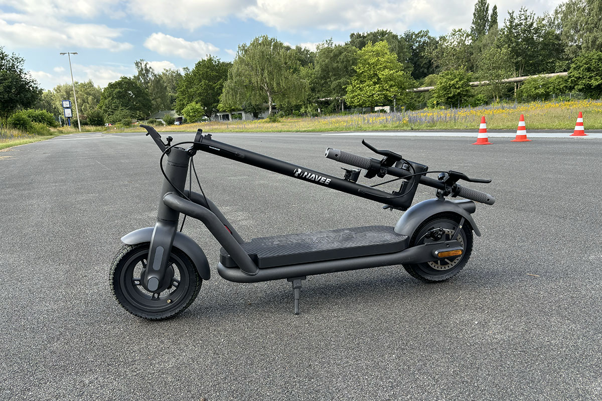 Eingeklappter E-Scooter im Profil auf Straße.