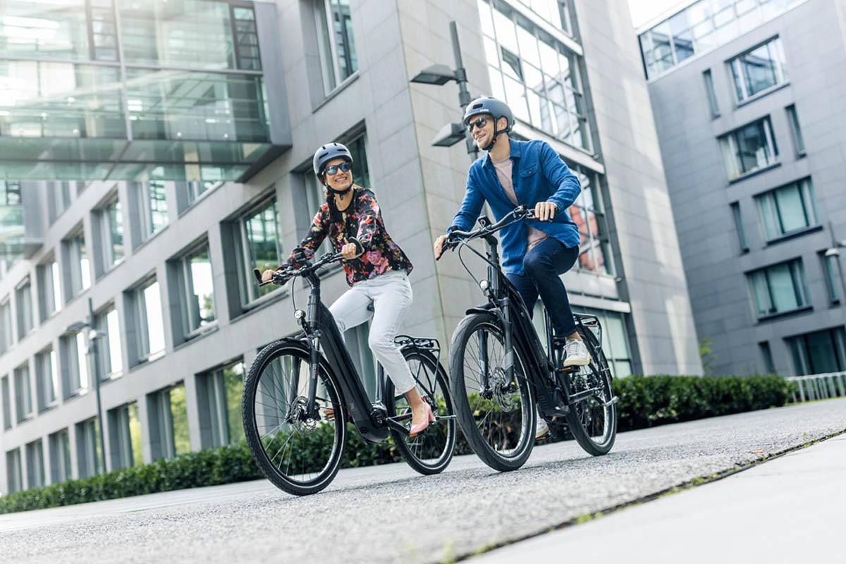 Zwei Menschen cruisen mit E-Bikes durch die Stadt.