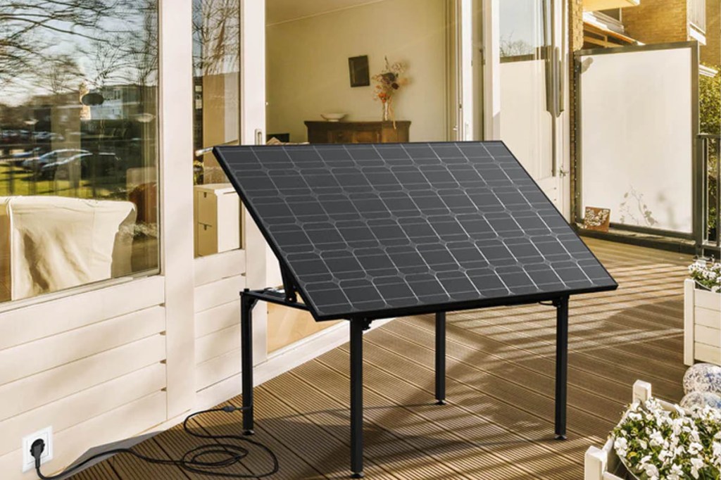 Eine Tischkonstruktion mit aufgestelltem Solarpanel auf einer Terrasse vor einem Haus.