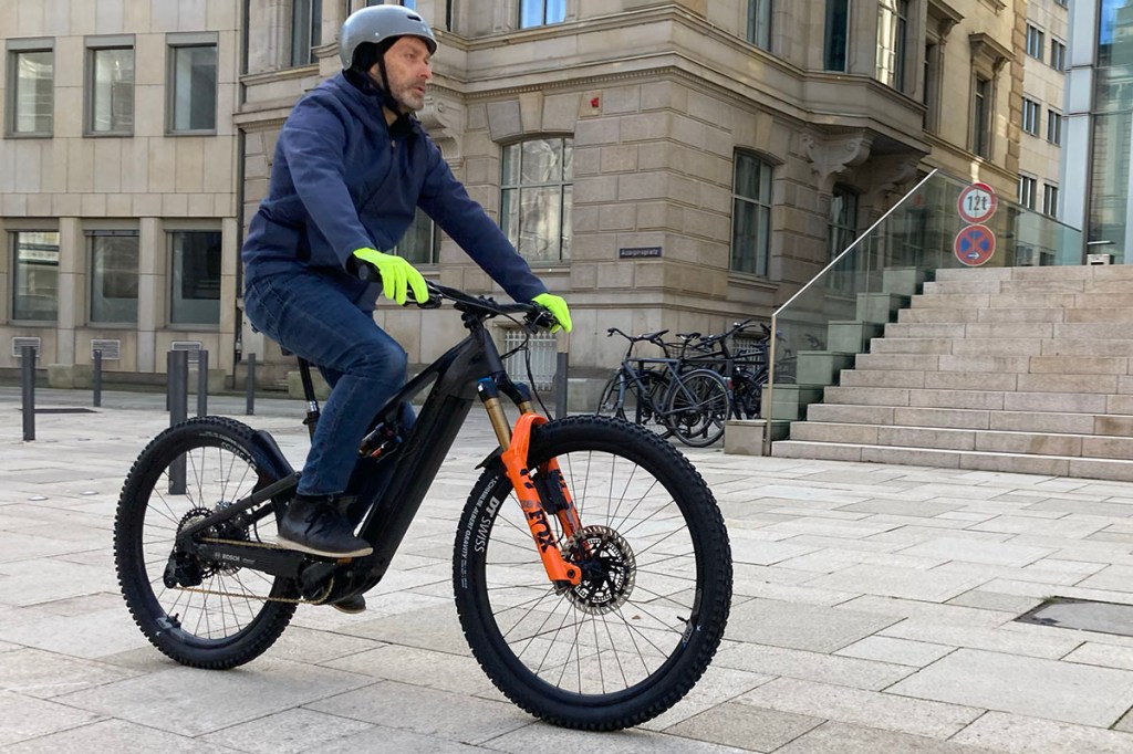 Mann fährt auf Fully-E-MTB über einen Platz in einer Stadt.