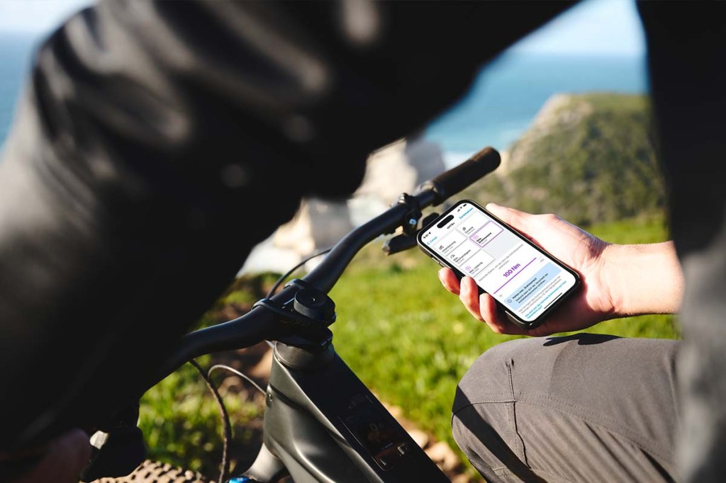 Anschnitt Lenker eines Fahrrads, man sieht eine Hand, die ein Smartphone festhält