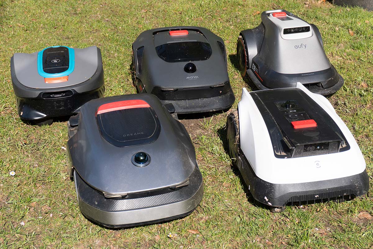 fünf Mähroboter stehen auf einem Rasen beieinander