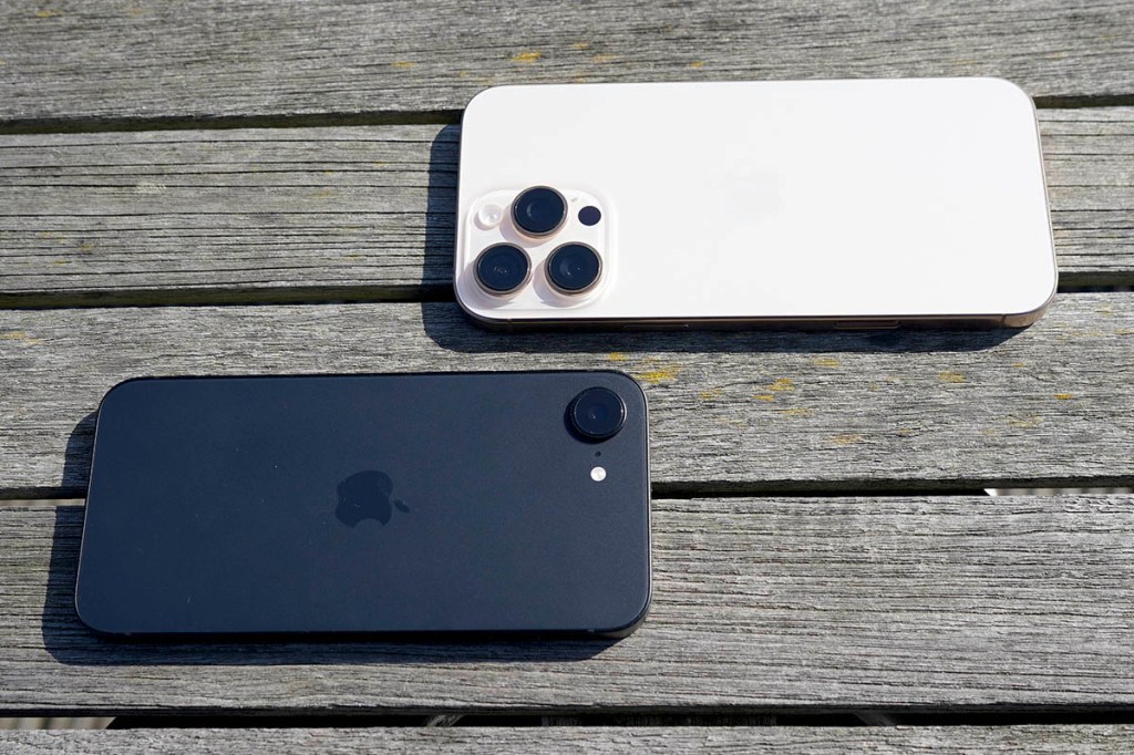 Das iPhone 16 Pro Max liegt neben dem iPhone 16e auf einem Holztisch.