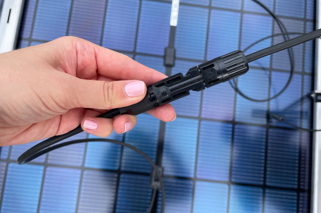 Kabel werden zusammengesteckt, im Hintergrund ein Solarpanel.
