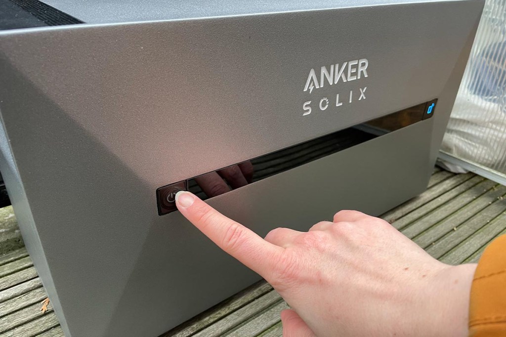 Eine Hand betätigt den Knopf der Anker Solix Solarbank 2 Pro.