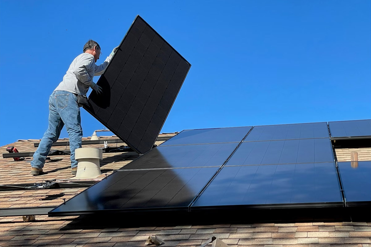 Eine Person installiert Solarpanels auf einem Dach.