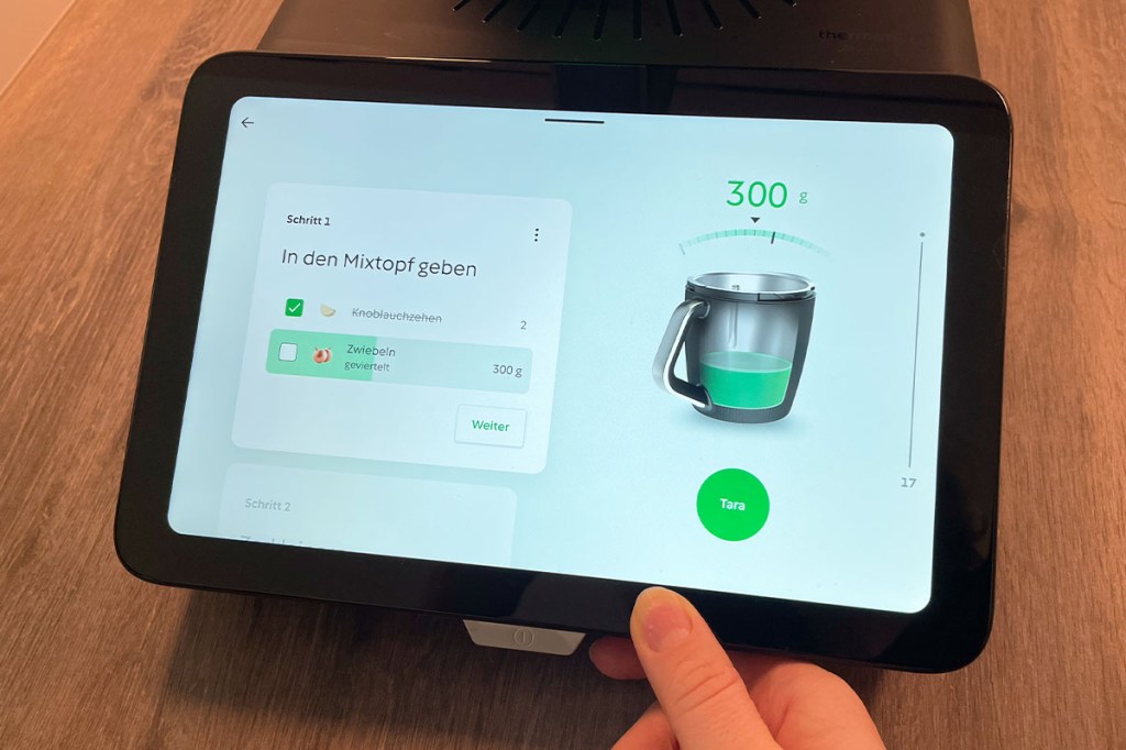 Das Display des TM7 mit einer Liste von Zutaten. Die obere ist abgehakt, die untere zeigt einen Balken, der zur Hälfte grün gefärbt ist.