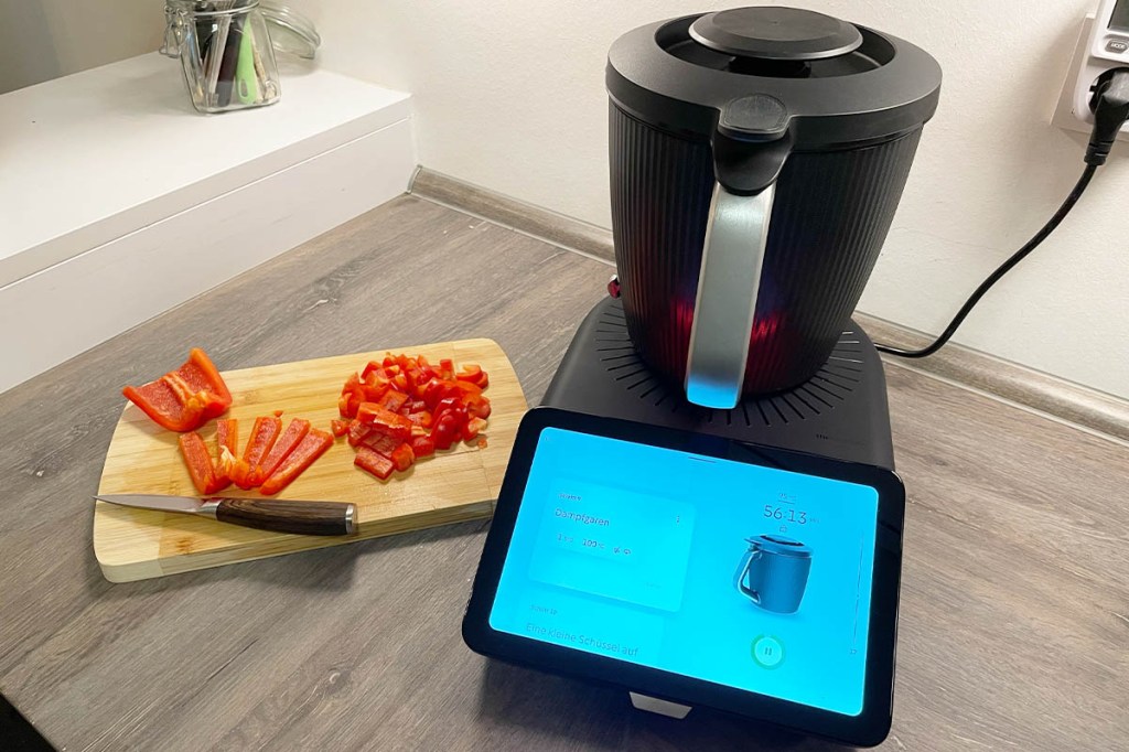 Der Thermomix TM7 in Betrieb. Daneben ein Schneidbrett mit Paprika und Messer.
