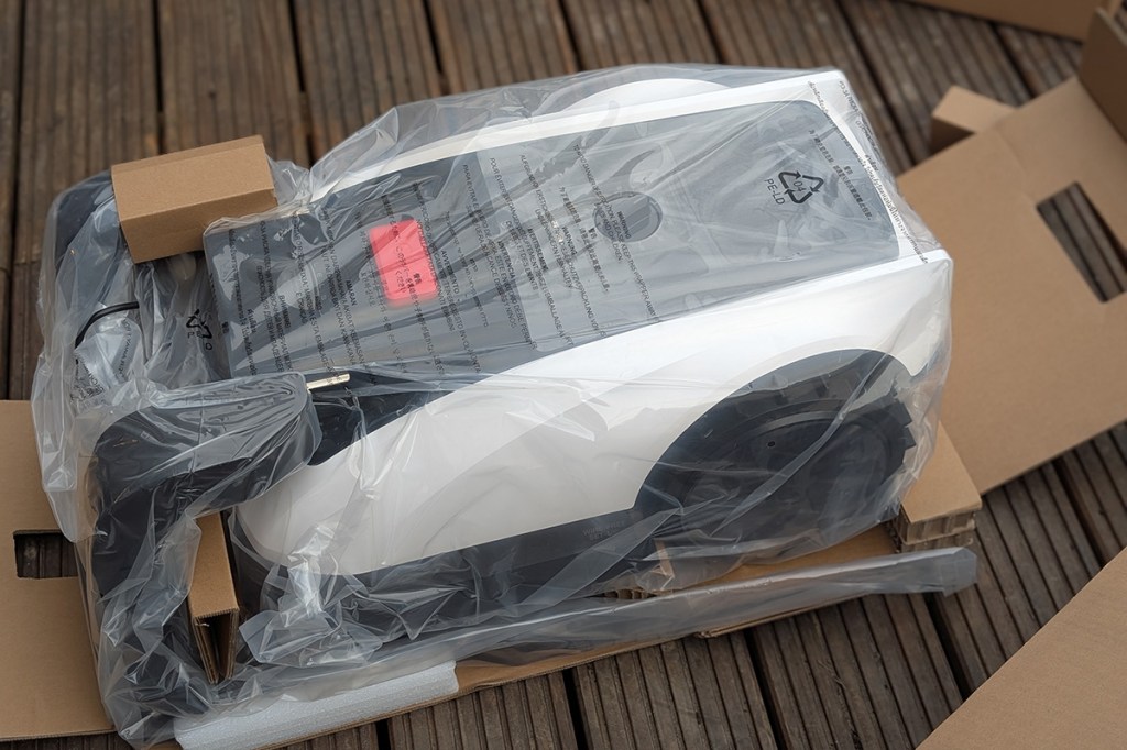 Der Ecovacs Goat o800 RTK noch in Plastikfolie im geöffneten Karton.