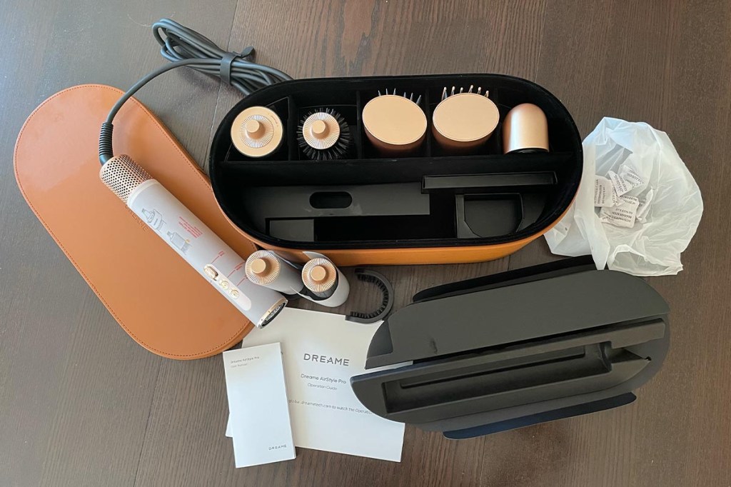 Der Dreame Airstyle Pro mit Case, Verpackungsbestandteilen und allen Aufsätzen auf einem Holztisch.