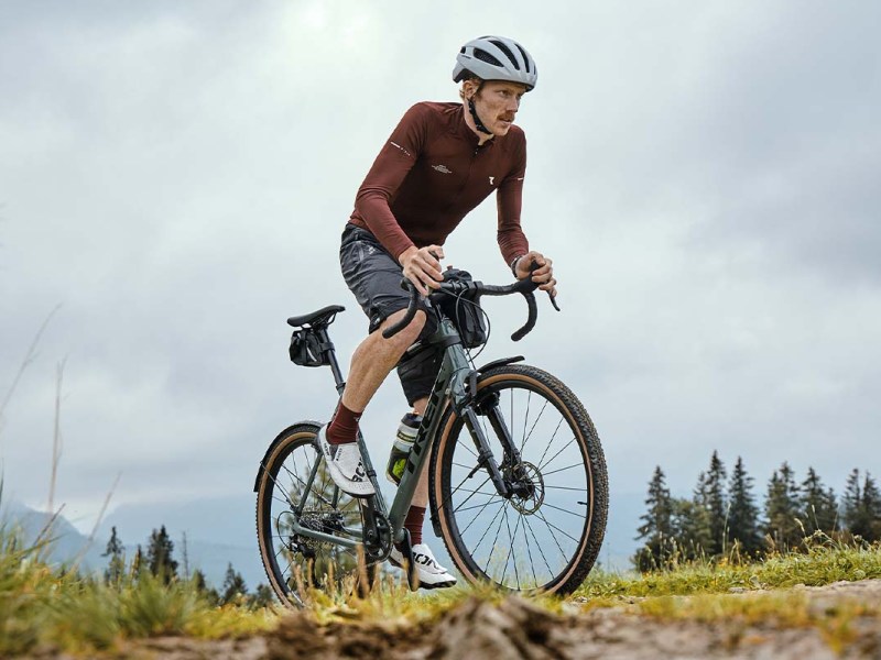 Mann fährt mit seinem Gravelbike durch die Natur