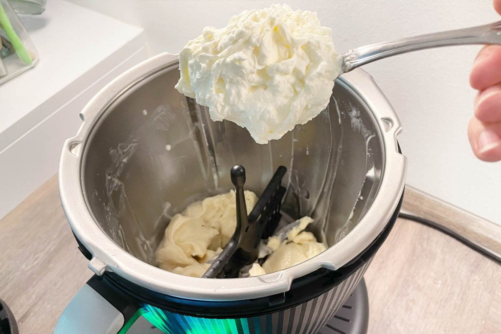 Sahne wird Löffelweise zur Vanillemasse im TM7 Mixtopf gegeben.